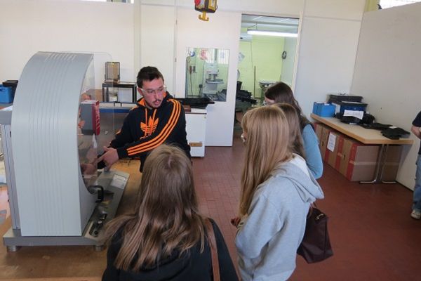 Samet Cakir hat sich schon immer für Autos interessiert – jetzt stellt er spezialisierte Kunststoffe-Bauteile für Autos her. Hier erklärt er gerade Schülerinnen beim Girls´ Day seinen Arbeitsplatz (Foto: Röchling Automotive).