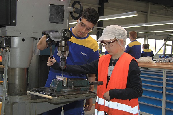 Mit tatkräftiger Unterstützung von Michelin-Azubi Kerem Tunc bedient die elfjährige Lena Dhom die Bohrmaschine (Foto: Michelin).